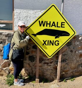 Author posing next to a "Whale Xing" sign