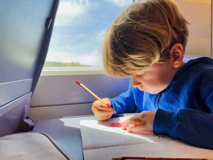 Little boy journals on a train
