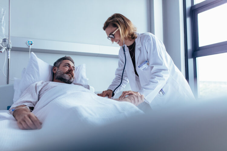 Doctor standing over patient is a hospital bed