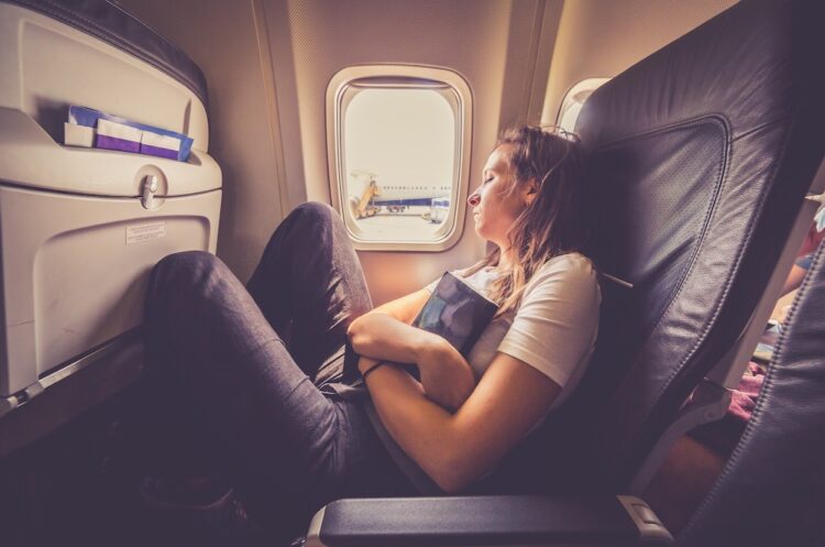 Woman sleeping in an airplane. holding a book. Passenger relaxes at a window in a flying aircraft after reading a book