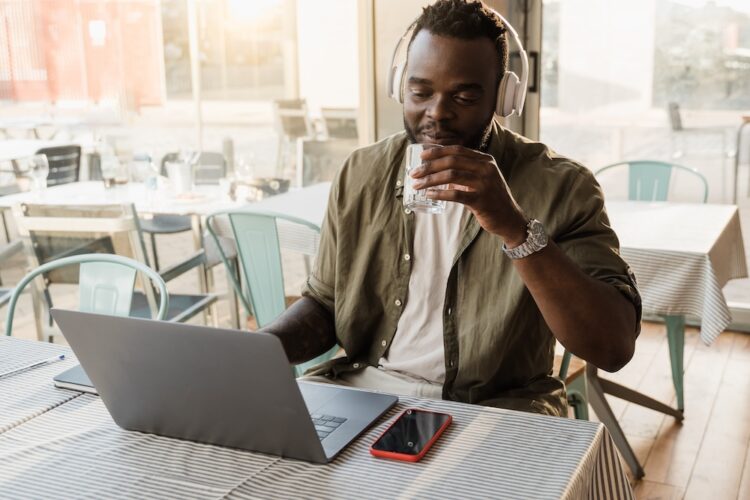 African american man using computer laptop doing video call meeting at bar restaurant - Focus on face