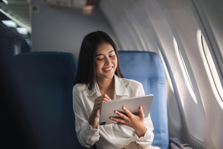 Asian travel woman watching movie on digital tablet in airplane