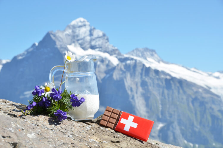 Swiss chocolate and jug of milk against mountain peak. Switzerland 