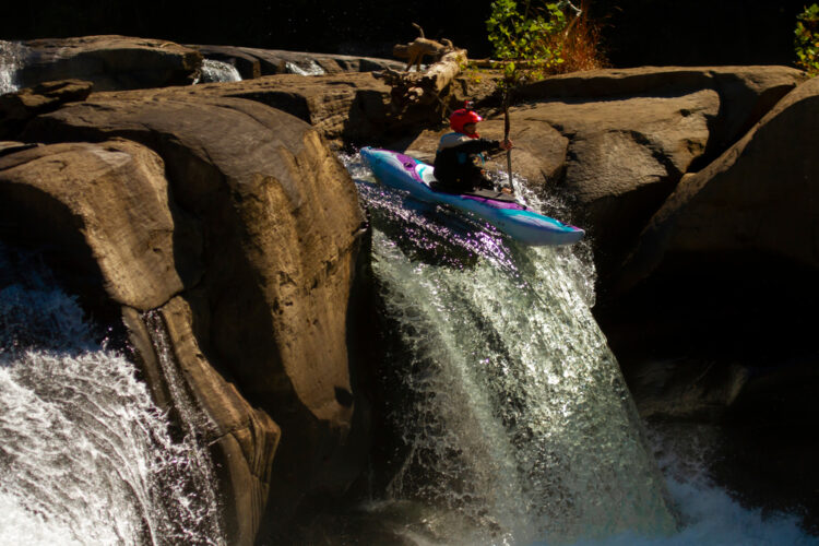 Kayaker braves a steep decent down a rock face