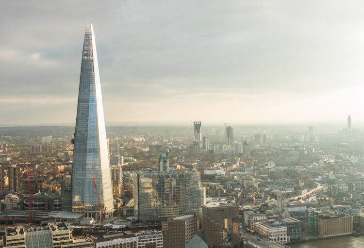 Alt text: "Aerial view of the iconic Shard skyscraper towering over London's skyline during a hazy sunset, capturing