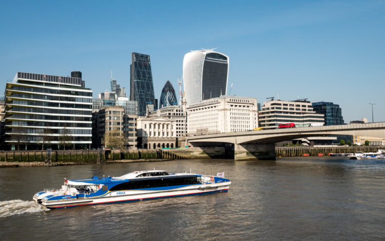 "Scenic view of the River Thames with an MBNA Thames Clipper commuter boat passing by modern London architecture and iconic skys