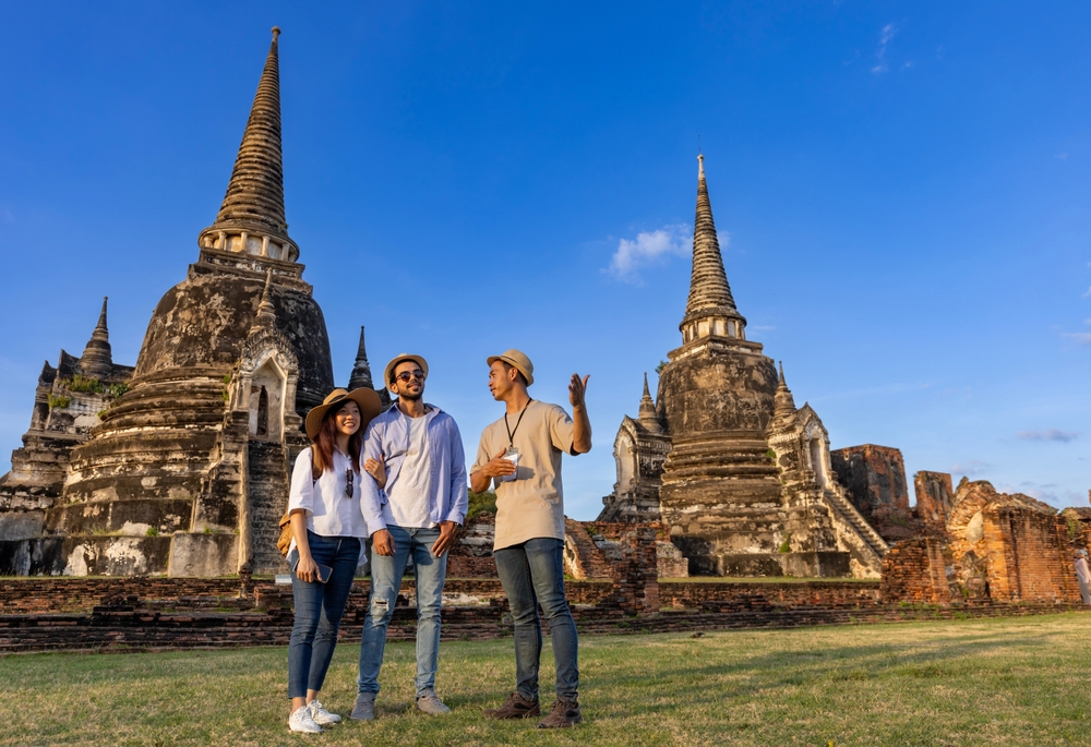 Thai local tour guide is explaining history of old Siam to the couple of tourist