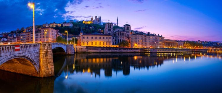 Ten Ways to Traverse Lyon Lyon city skyline at night, over the Pont Bonaparte Bridge, vibrant water reflections on the Saone River, Saint George Church, and La Basilique Notre Dame de Fourvière in France