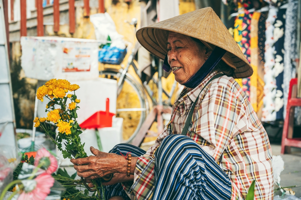 Vietnamese woman selling flowers at an Asian market