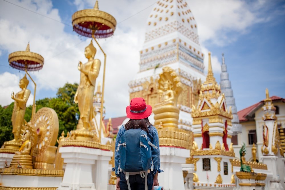 A solo woman traveler looks at a Buddhist temple shrine