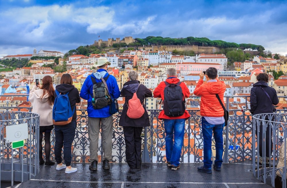 Group of tourists watching the cityscape of Lisbon and taking pictures of the castle architecture in Portugal