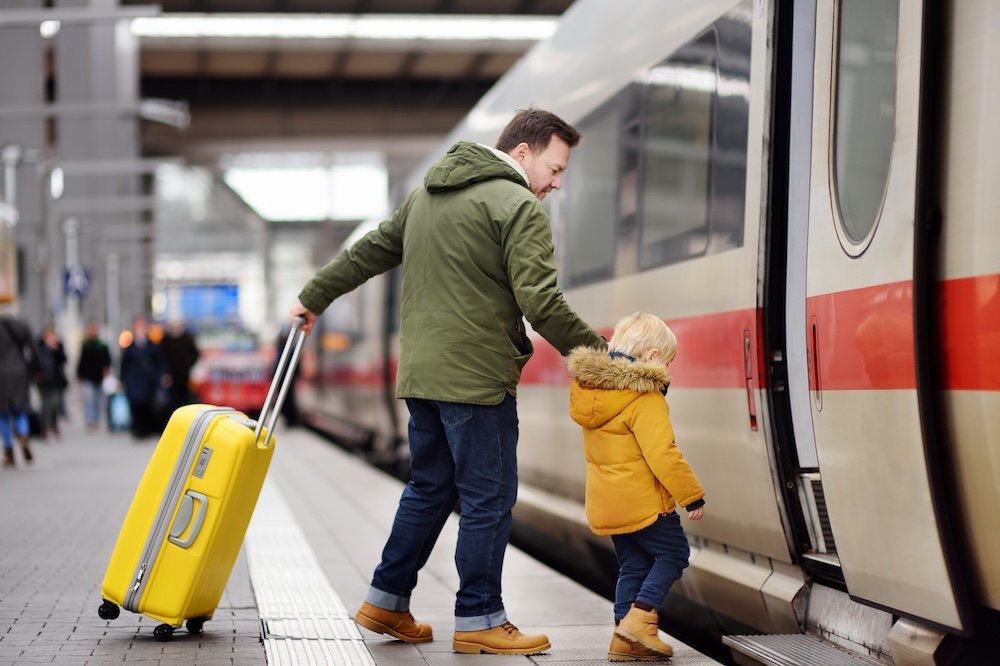 Adult and child boarding train with suitcase